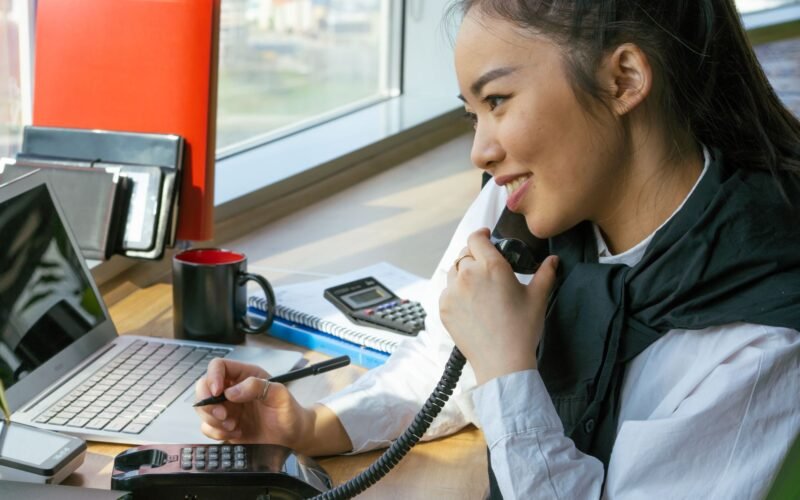 Mulher jovem sorrindo usando notebook em casa, estudando um curso de auxiliar administrativo online com certificado.