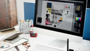Pessoa estudando design gráfico em um notebook, com softwares de edição abertos e um certificado digital ao fundo.