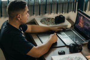 Jovem designer criando um portfólio digital em um computador, com elementos gráficos e ferramentas de design ao redor, simbolizando a construção de um portfólio.