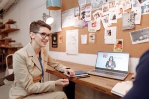 Pessoa sorrindo e usando fones de ouvido em frente a um laptop, simbolizando aprendizado de inglês para aprimoramento profissional.