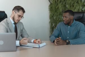 Mulher sorrindo e confiante durante uma entrevista de emprego em inglês, com um laptop e anotações à frente.