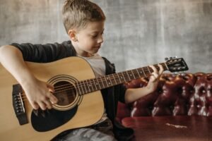 Pessoa tocando violão com partituras e um metrônomo ao lado, simbolizando o aprendizado.