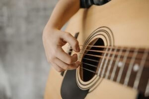 Mão esquerda de um violonista fazendo uma pestana perfeita em um violão de cordas de nylon, sem trastejar e com expressão de conforto.